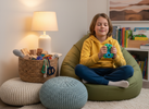 School-aged child sitting in a cosy calm-down corner at home with a warm lamp and a basket of quiet fidgets, using a tactile fidget to self-regulate