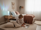 Child relaxing in a calm sensory-friendly bedroom with soft lighting and a glowing visual sensory lamp