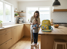 Parent helping a child get ready in the morning while the child holds a small quiet fidget, bright kitchen light