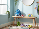 Bright, playful home entryway with school bag, shoes, and a small sensory fidget kit on a bench