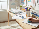 Bright, playful teenager’s study desk with open homework, colourful pens, and a small sensory fidget next to the books.