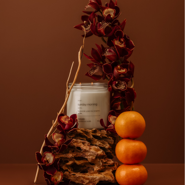 SUNDAY MORNING DOUBLE WICKED SOY CANDLE (16oz / 453g) with deep red orchids and stacked oranges, calm setting.
