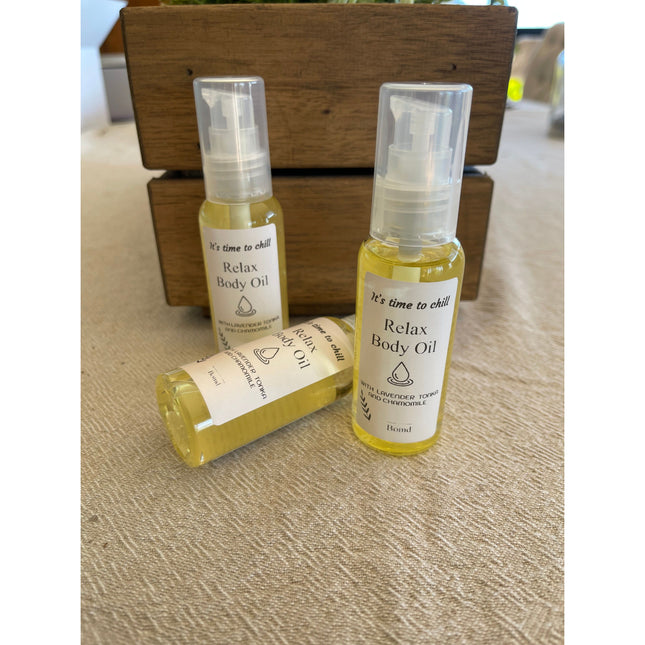 Three bottles of Relax Body Oil Massage and Moisturise displayed on a textured surface with wooden background helping families thrive.