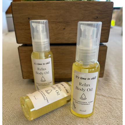 Three bottles of Relax Body Oil Massage and Moisturise with lavender and chamomile on a wooden surface, calming tone.