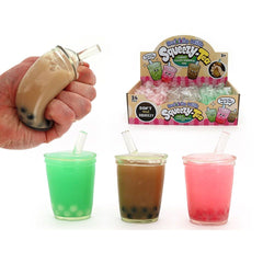 Hand holding a bubble tea shaped squishy beside three colorful cups and a display box