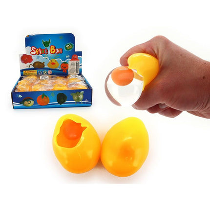 Hand squeezing a yellow Water Squeeze Splatter Chicken Egg - 7cm toy with orange yolk inside and display box in background