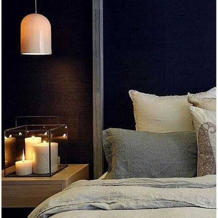 Off White Pillar Candle Rustic Relic Design glowing on bedside table in cozy, calming bedroom setting