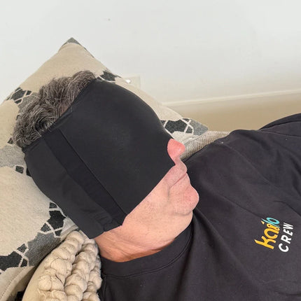 Person lying down wearing the Block Out Cooling Head Mask – a cool ‘hug’ for your head in black color.
