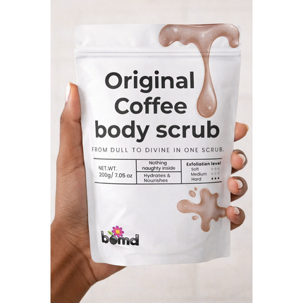 Hand holding Coffee Body Scrub Original Warm Vanilla Blend pouch with brown scrub splash on white background Helping families thrive with tools to calm connect and support