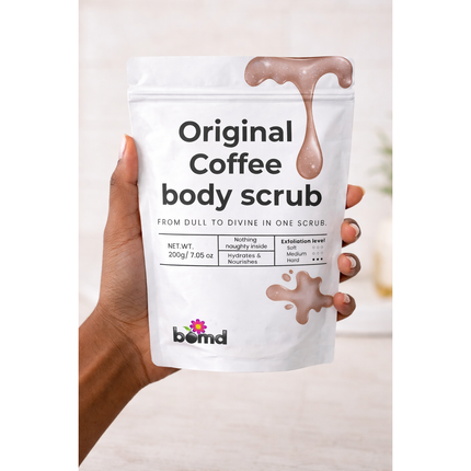 Hand holding Coffee Body Scrub Original Warm Vanilla Blend package with creamy scrub drips, helping families thrive.