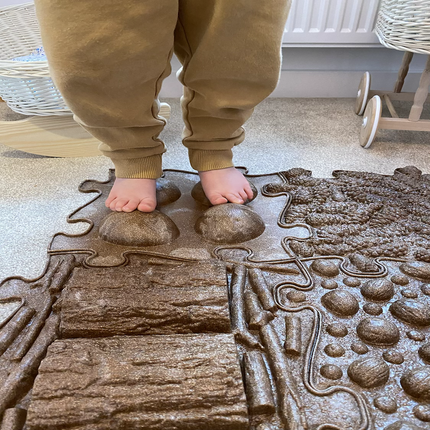 Child standing barefoot on textured brown sensory playmat pieces designed for tactile exploration with Muffik Eco Sensory Playmat - Individual.