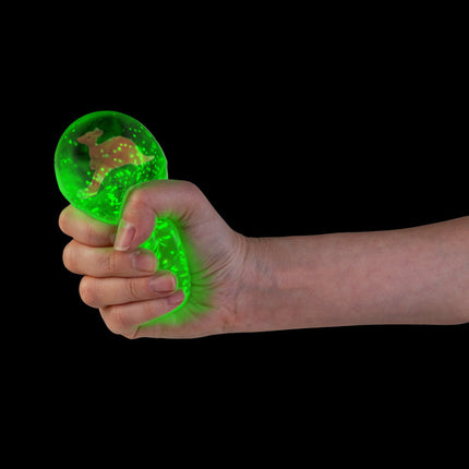 Hand squeezing glowing green Smooshos Super Squeeze Diamond Sphere GID Kangaroo sensory fidget toy against black background