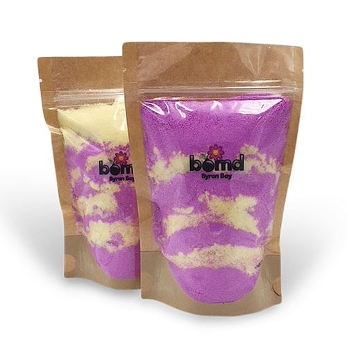 Two resealable pouches of FOMO Fizzing Bubble Bath Dust - thick luscious bubbles with purple and cream swirls.