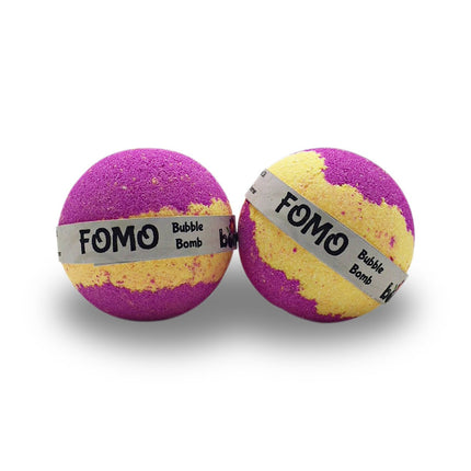 Two purple and yellow bath bombs with labels displaying FOMO Bubble Bath Bomb 6 Pack Creates Thick Luscious Bubbles That Last for Ages - Never Miss a Party