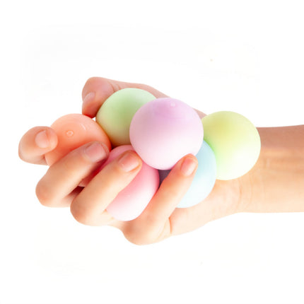 Hand squeezing Smoosho's Glow-in-the-Dark Sticky Splat Ballz - Set of 3 in soft pastel colors for sensory play