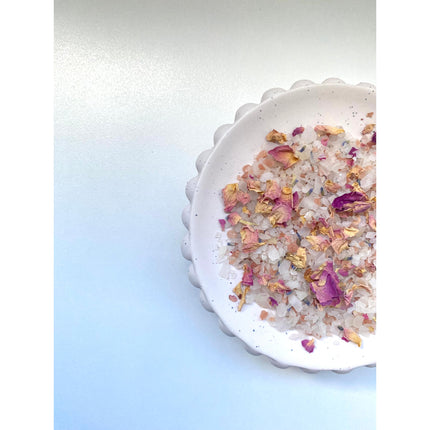 White dish with pink and yellow flower petals and crystals of #5 Flo - Just For Her - Magnesium Bath + Foot Salts helping families thrive with tools to calm connect and support