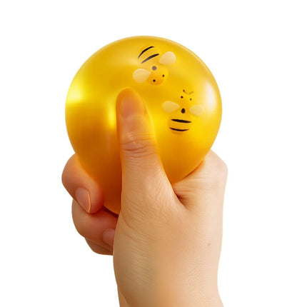 Honey Drop Ball yellow sensory fidget ball being squeezed in a hand