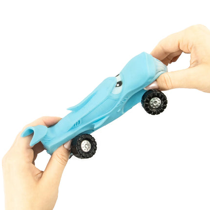 Hands squeezing a blue shark-shaped Stretch Wheels sensory fidget toy with black wheels for tactile play