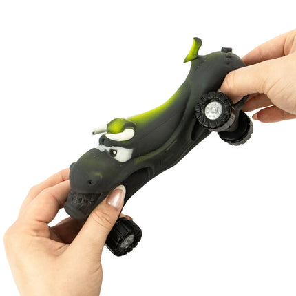 Hands squeezing a black and green dinosaur-shaped Stretch Wheels sensory fidget toy with large wheels