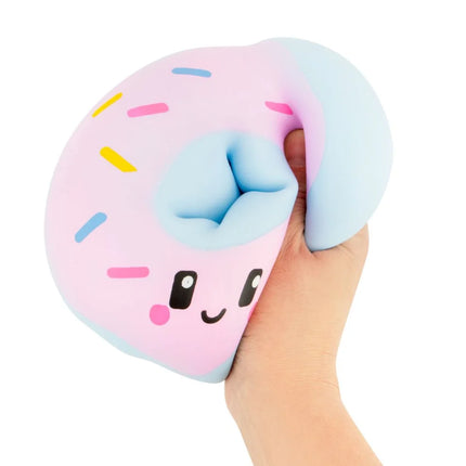 Hand holding a pastel pink and blue donut-shaped squishy with a smiling face and sprinkles