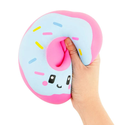 Hand squeezing a pastel pink and blue donut shaped squishy with a smiling face and sprinkles