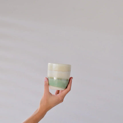 Hand holding a ceramic cup with soft green and cream tones for the SUNDAY MORNING GIFT BOX, helping families thrive.