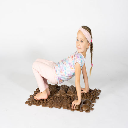 Child playing on a textured brown Muffik Eco Sensory Playmat - Individual, helping families thrive with tools to calm connect and support