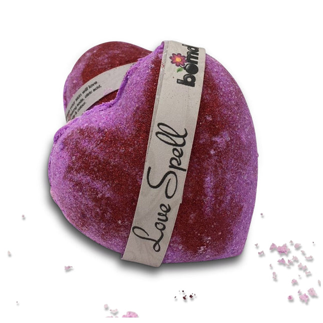 Heart-shaped red and purple Love Spell Bubble Bath Bomb with Glitter wrapped by a paper band helping families thrive.