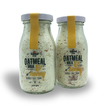 Two glass jars of Oatmeal Milk & Honey Moisturising Bubble Salt Soak with Himalayan Rock Salt with yellow labels and white caps