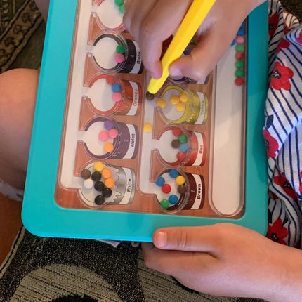 Child’s hands using a yellow magnetic wand to move colored balls on a Colour & Number Maze Magnetic Pad - Magnetic Colour Sorting Maze with labeled color sections.
