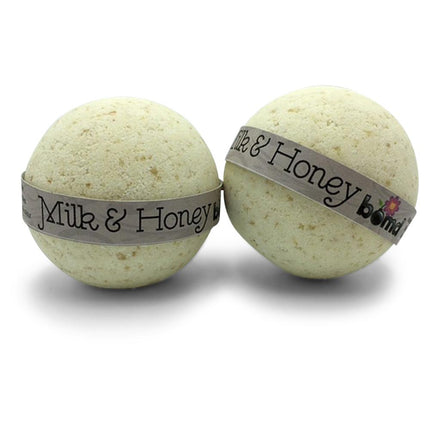 Two round bath bombs with oatmeal texture wrapped in labels, Oatmeal Milk & Honey Moisturising Bath Bomb Set of 6.