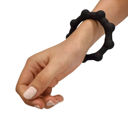Hand wearing black silicone Octopop - Quiet. Wearable. Satisfying sensory fidget bracelet against white background
