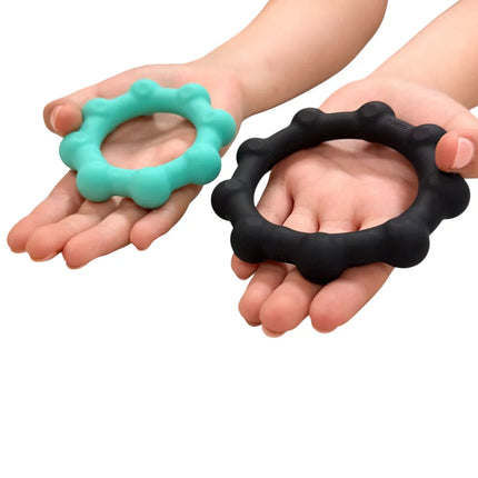 Hands holding two Octopop - Quiet. Wearable. Satisfying sensory fidget rings in black and teal colors.