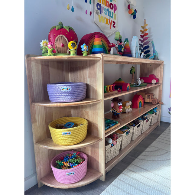JORA Corner 4-Tier Corner Shelf holding colorful baskets and toys in a bright children’s playroom setting