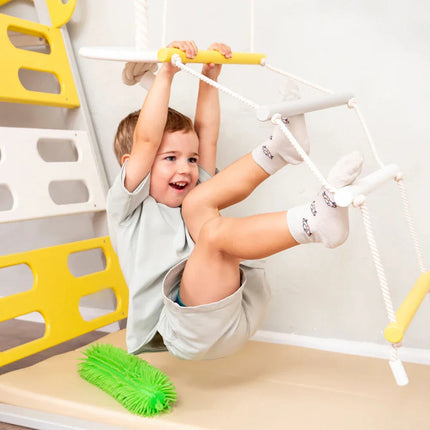 Child happily playing on indoor wooden climbing frame with rope ladder in Wooden Teepee Playground setup
