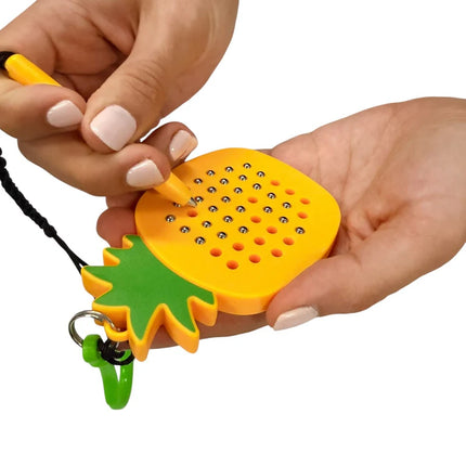 Person using the Pineapple Magnetic Pad Keyring, a bright yellow and green sensory toy with small steel balls, held in both hands.