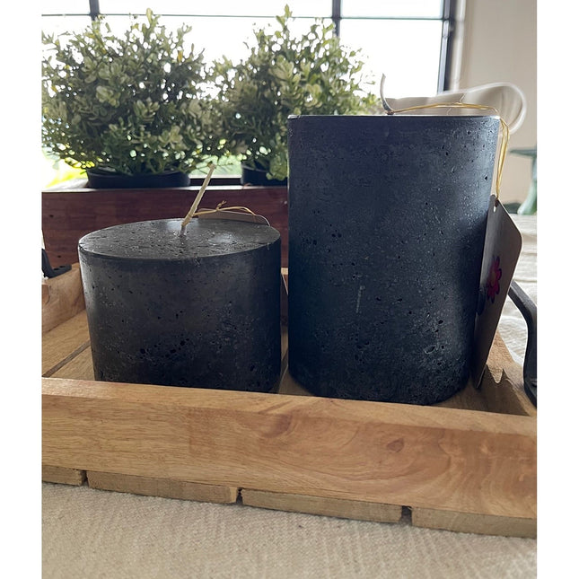 Charcoal Black Pillar Candle Stone Relic Finish with textured surface, placed on wooden tray by green plants nearby