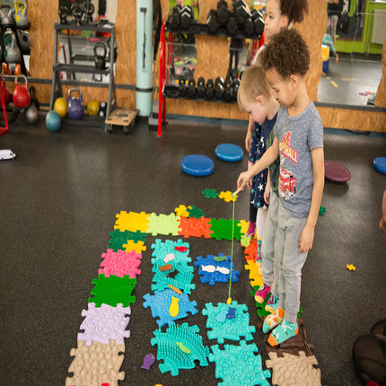 Children playing with colorful Seashells Sensory Playmat - SOFT pieces in an indoor activity space designed for sensory play.