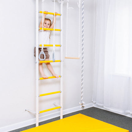 Child climbing a white and yellow Sensory Swedish Wall Bars with attached rings and rope swing in a bright room