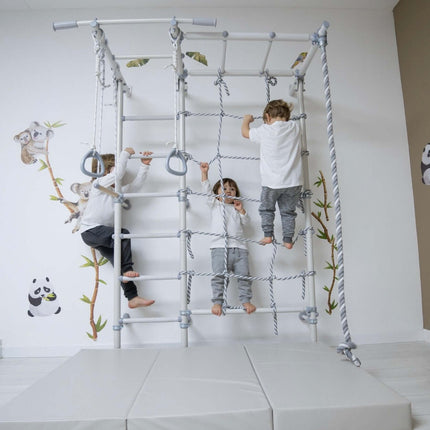 Three children playing on Swedish Giant Wallbars - S7 indoor climbing frame with rope and gymnastic rings