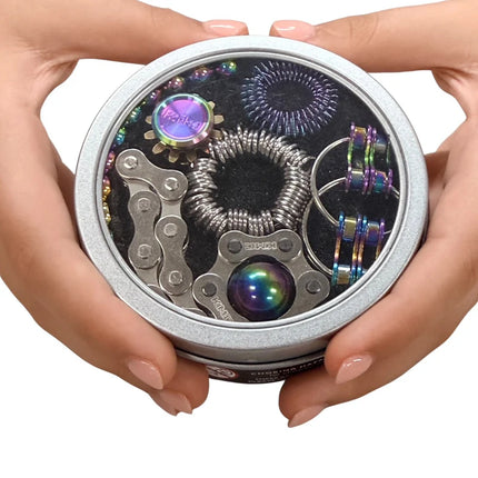 Hands holding The Works Fidget Kit featuring metallic and iridescent sensory tools inside a round tin container.