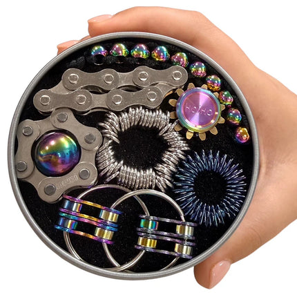 Hand holding a round tin of The Works Fidget Kit with assorted colorful metallic fidget tools inside.