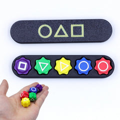 Squid Game 2 Gonggi & Case Korean Grab 5 stone sieves+rectangular box held in hand with colorful symbols on black case helping families thrive.