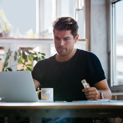 Man at desk using laptop while holding Metal Fidget Slider Toy, EDC Fidget Toy for Adults, Stress Relief for Anxiety.