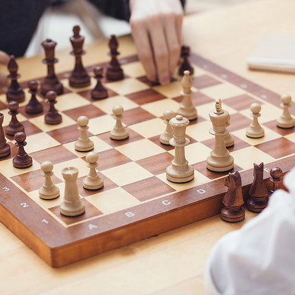 Chess Board Games Folding Large Chess Wooden Chessboard Set Wood Toy Gift in use during a thoughtful gameplay session.