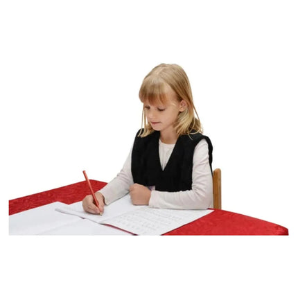 Child wearing Weighted Shoulder Wraps focused on writing at a table, helping families thrive with tools to calm and support.