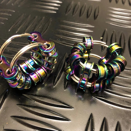 Caged Fidget sensory toy with iridescent metal rings on a textured black surface for calming and focus.