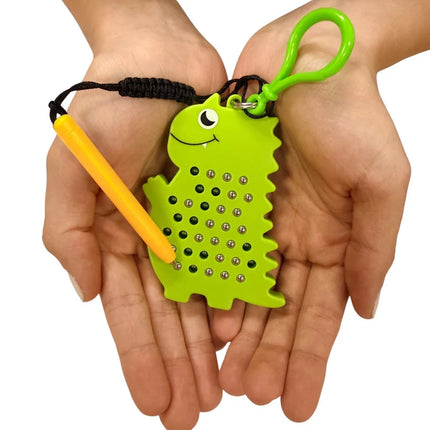 Hands holding a bright green Dinosaur Magnetic Pad Keyring with a yellow magnetic pen attached, designed for sensory play and fine motor skills.