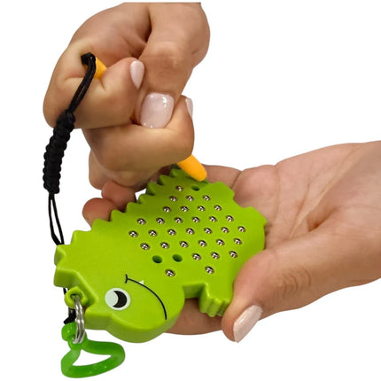 Person using a yellow magnetic pen on a green dinosaur-shaped sensory toy held in hand, named Dinosaur Magnetic Pad Keyring.