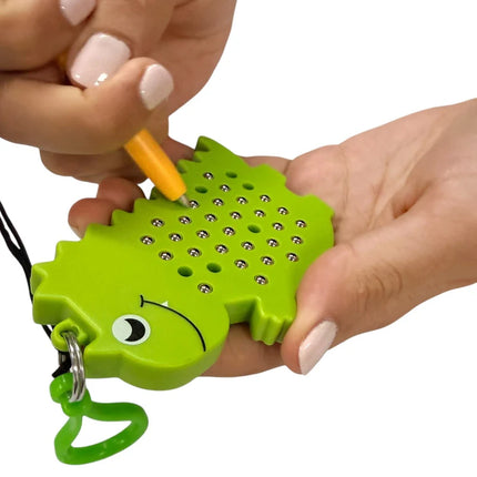 Person holding a green dinosaur-shaped sensory toy using a small magnetic pen on the Dinosaur Magnetic Pad Keyring.